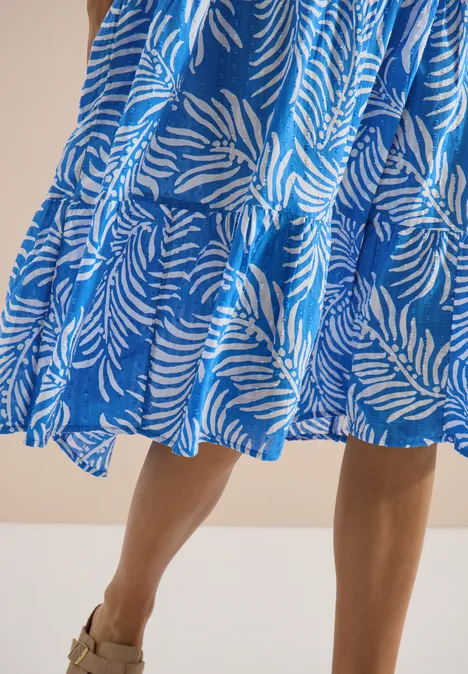 Midikleid mit Split Neck und Print ethereal blue Frau in blau-weiß gemustertem, knielangem Kleid im Zebra-Design und Sandalen.