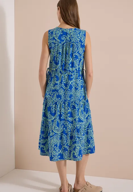 Midijurk met V-hals en print surf blue Vrouw van achteren in een knielange, mouwloze blauw-groene paisleyjurk.