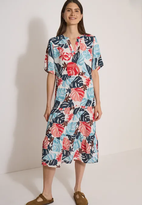 Robe mi-longue à col fendu et imprimé light alabaster white Une femme porte une robe midi colorée à motif de feuilles tropicales.