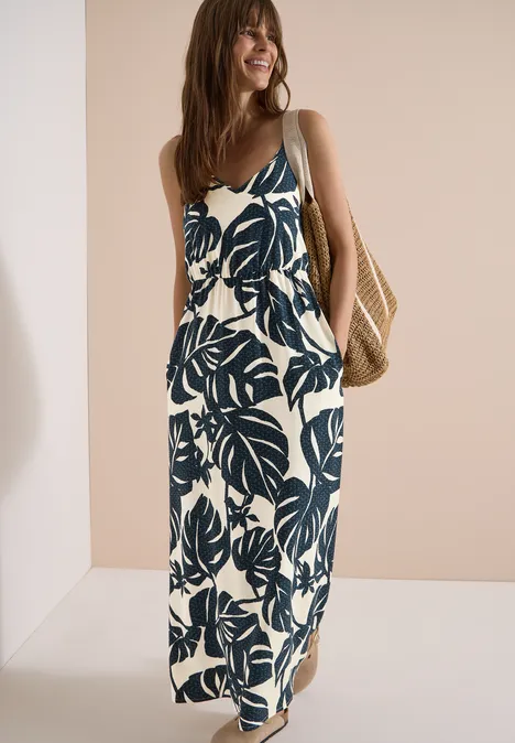 Maxikleid mit V-Neck und Print palm breeze green Frau trägt sommerliches Maxikleid mit blauem Blattmuster und Korbtasche.
