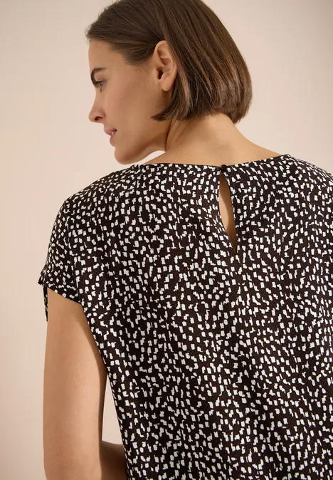 Robe mi-longue avec manchons brown cacao Vue de dos d'une femme aux cheveux courts bruns portant une blouse noire à petits motifs blancs.