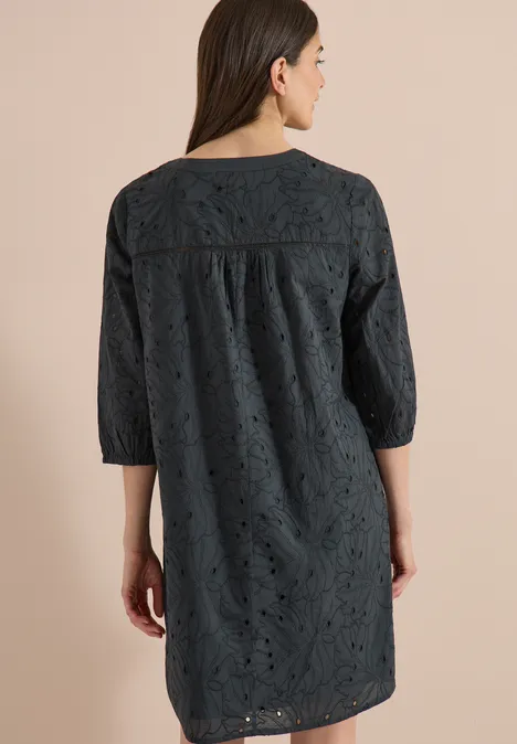 Robe longueur genou avec manches 3/4 et broderie palm breeze green Une femme de dos portant une robe noire courte en dentelle à manches 3/4.