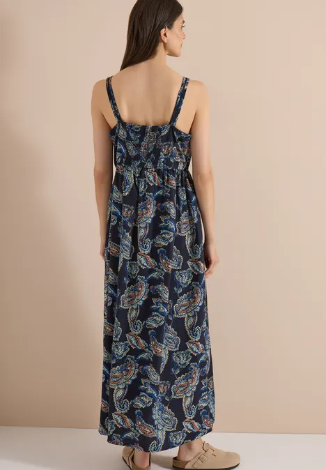 Rückenansicht einer Frau in ärmellosem, blau gemusterten, langen Sommerkleid mit Spaghettiträgern