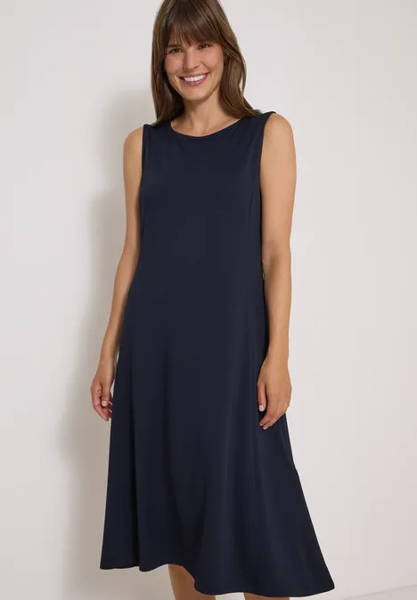Midi-jurk met ronde hals van jersey urban dark blue Vrolijke vrouw in een donkerblauwe, mouwloze maxi-jurk voor een lichte achtergrond.