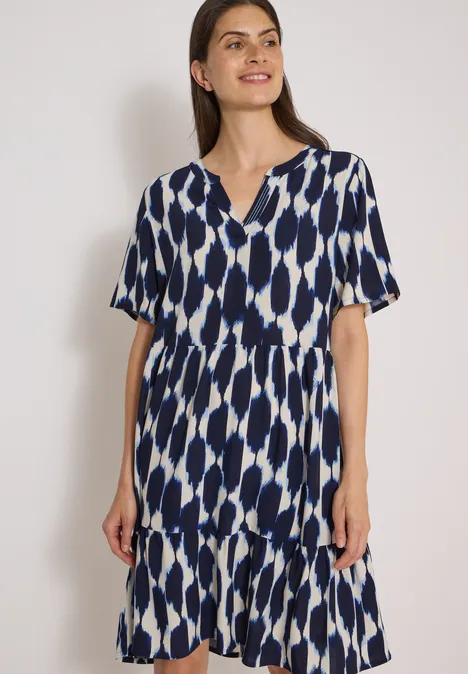 Knielanges Kleid mit Split Neck und Struktur urban dark blue Frau trägt blau-weiß gemustertes, knielanges Kleid mit V-Ausschnitt und Stufensaum.