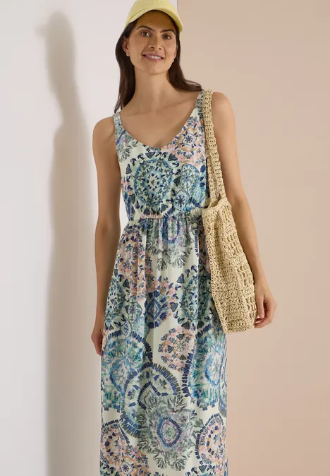 Maxikleid mit V-Neck und Print vanilla white Eine lächelnde Frau trägt ein bunt gemustertes, ärmelloses Maxikleid, eine Strohtasche und eine gelbe Mütze.