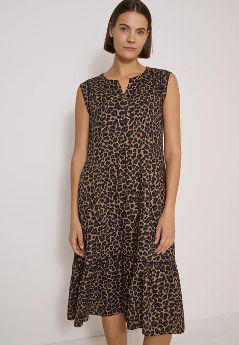 Midikleid mit Split Neck und Print creamy mocha Frau trägt ärmelloses midilanges Kleid mit Leoprint und Rüschen am Saum vor neutralem Hintergrund.