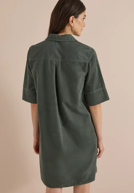 Vue de dos d'une femme portant une robe-chemise vert foncé en velours côtelé à manches mi-longues.