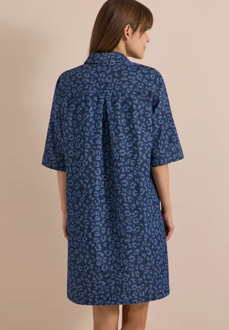 Frau von hinten in lockerem, blauem Hemdkleid mit kurzem Arm und dezentem Muster.