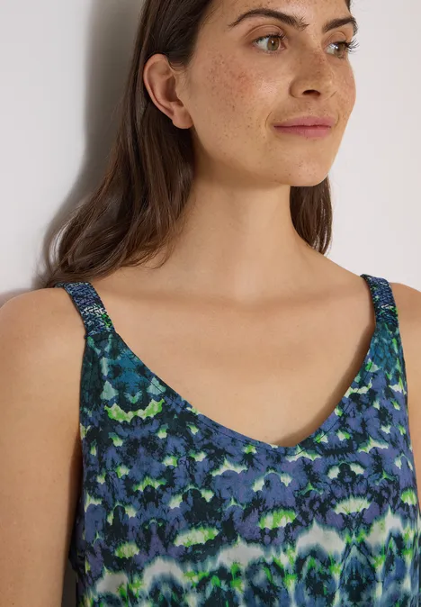 Maxikleid mit V-Neck und Print urban dark blue Frau trägt ärmelloses Oberteil mit blau-grünem abstraktem Muster.