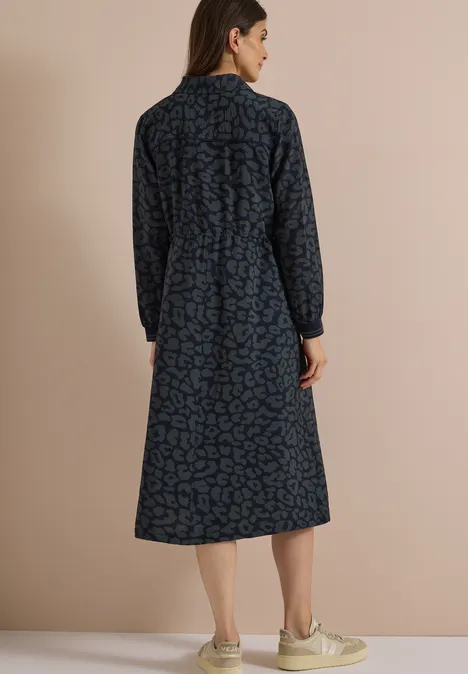 Frau von hinten in dunkelblauem, gemustertem Midi-Kleid mit langen Ärmeln und Kragen.