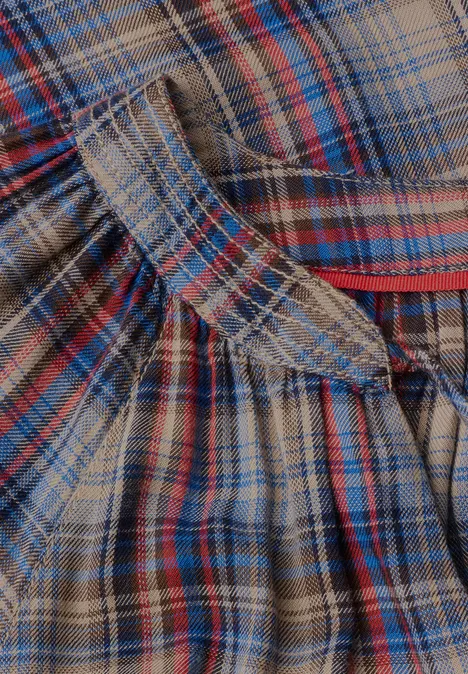 Close-up van geruit flanellen stof in bruin, blauw en rood met plooien en stikdetails.