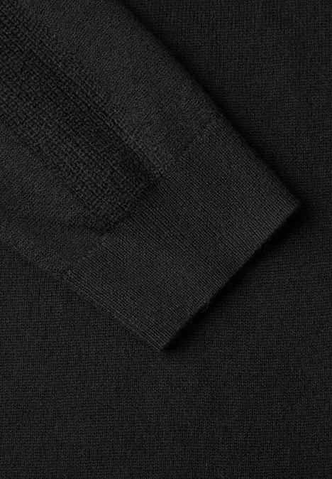 Kniehoge jurk met col Black Close-up van een zwarte gebreide trui, zichtbare mouwboord en fijne textuur.