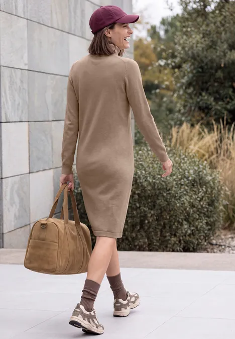 Knielanges Kleid mit Rollkragen creamy mocha melange Eine von hinten gesehene Frau in beigem Midikleid, braunen Sneakers und Cap, trägt eine große Tasche.