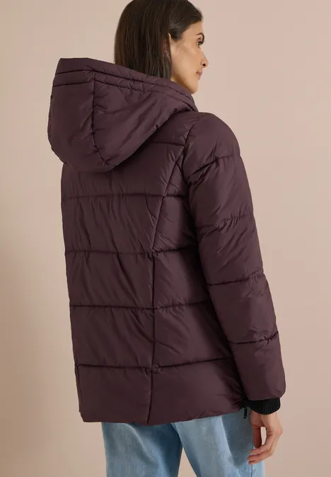Frau trägt lila gesteppten Winterparka mit Kapuze, Rückansicht.