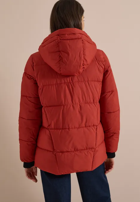 Puffer-Jacke in Midi-Länge mit Kapuze light russet red Rückenansicht einer Person mit roter gesteppter Jacke und Kapuze, kombiniert mit blauen Jeans.