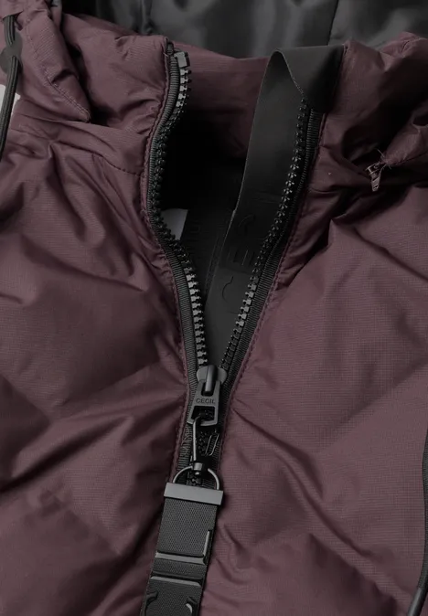 Veste matelassée à capuche et fermeture éclair berry red Nahaufnahme eines Reißverschlusses an einer dunkellila Jacke.