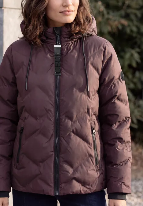 Veste matelassée à capuche et fermeture éclair berry red Frau trägt gesteppte, dunkelbraune Winterjacke mit Kapuze.