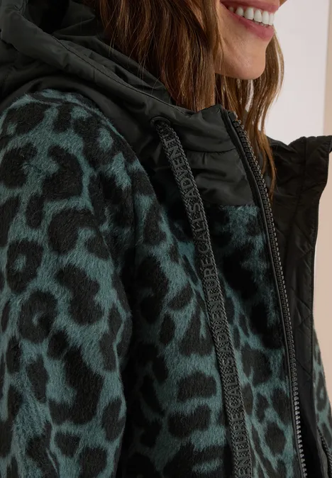 Frau trägt grün-schwarze Fleecejacke mit Leopardenmuster und Kapuze.