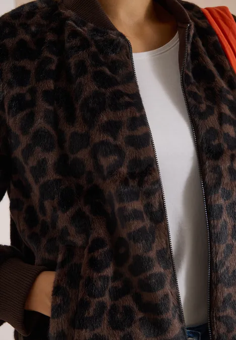 Nahaufnahme einer Person in weißem Shirt und braunem Leopardenmuster-Cardigan.