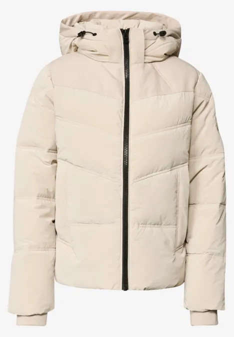 Veste matelassée à capuche avec détails en sergé powder beige Doudoune beige clair à capuche, fermeture zippée centrale et poignets côtelés, style épuré et chaud.