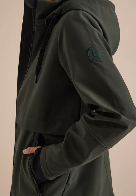 Dunkelgrüner Softshell-Parka mit Kapuze, Fronttasche und Logo-Patch am Ärmel.