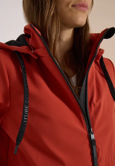 Rote Softshell-Jacke mit Reißverschluss und schwarzem Kordelzug.