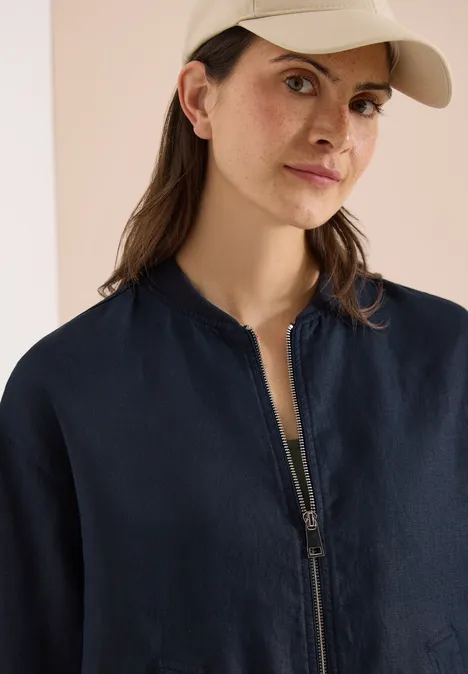 Blouson aus Leinen mit Zipper universal blue Eine Person in blauer Bomberjacke, hellem Top und beiger Baseballcap vor neutralem Hintergrund