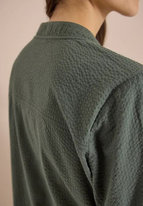 Nahaufnahme des Rückens einer Person in texturierter dunkelgrüner Jacke.