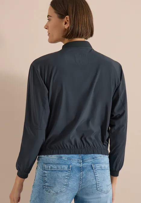 Personne de dos portant une veste sombre et un jean bleu.
