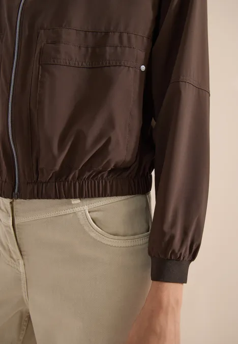 Blouson uni à fermeture zip brown cacao Gros plan d'une personne portant une veste marron zippée et un pantalon beige.