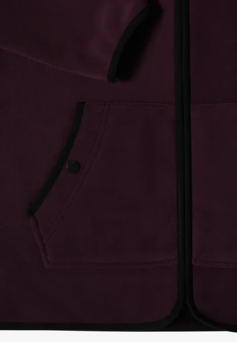 Close-up van een bordeaux fleecevest met rits en voorknopzak.