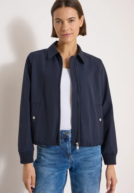Kurtka Blouson z kołnierzem koszulowym urban dark blue Kobieta w granatowej kurtce na białej koszulce i dżinsach na jasnym tle.