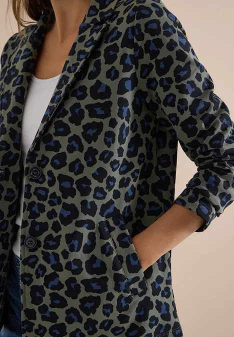 Blazer ample à boutons et imprimé dried olive green Veste verte à imprimé léopard bleu, poches plaquées, portée décontractée sur un débardeur blanc.
