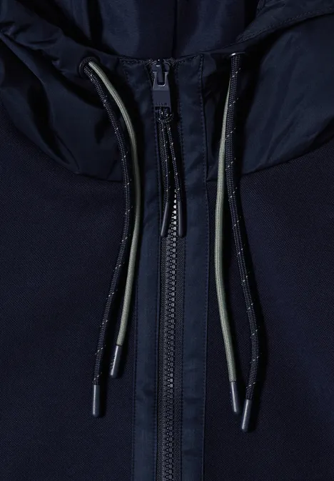 Close-up van een donkerblauwe rits met koordjes en metalen uiteinden.
