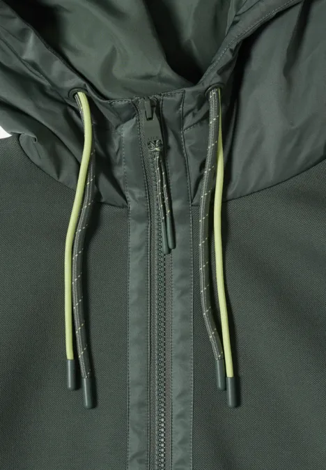 Nahaufnahme einer dunkelgrünen Jacke mit Reißverschluss und olivgrünen Kordeln an der Kapuze