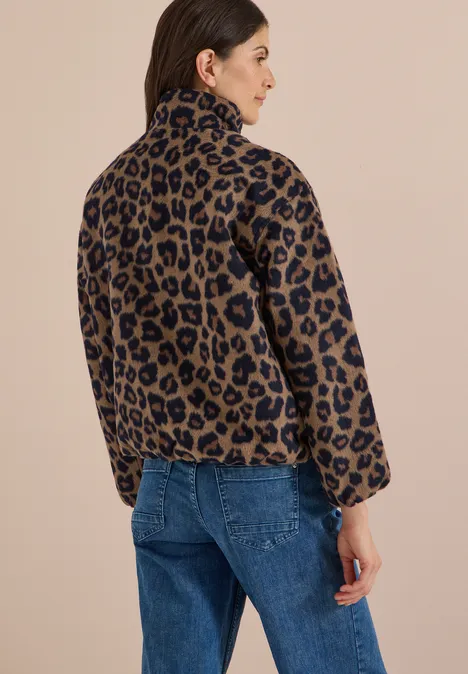Vrouw van achteren in een bruine-zwarte leopardprint fleecejas en blauwe jeans.
