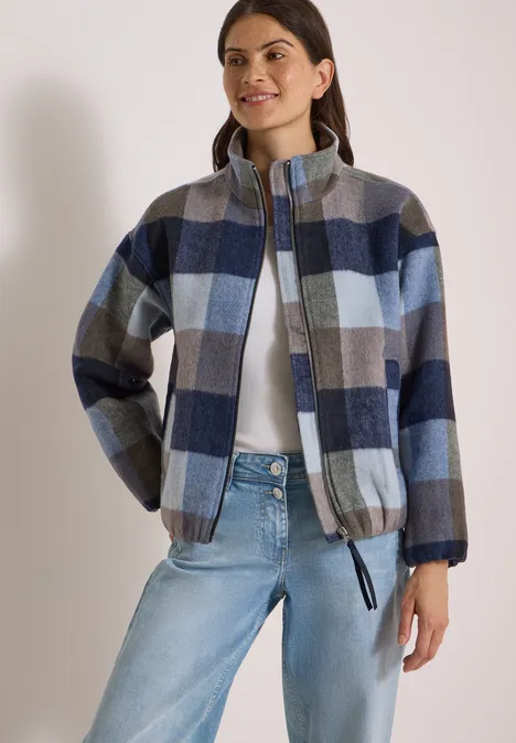 Blouson à col montant et motif à carreaux urban dark blue Femme portant une doudoune à carreaux bleus, gris et crème, col montant et fermeture éclair.