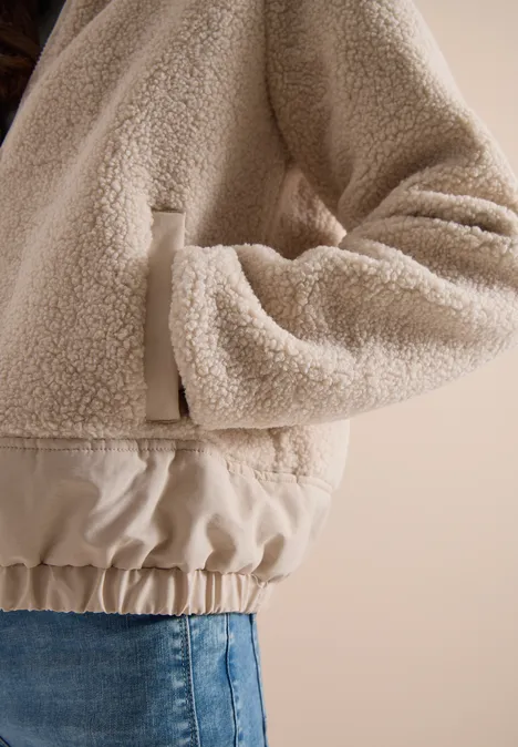 Teddy-Jacke mit Softshell-Details teddy vanilla white Beige Teddy-Fleecejacke mit elastischem Bund, Hand in Tasche gesteckt, kombiniert mit Jeans.