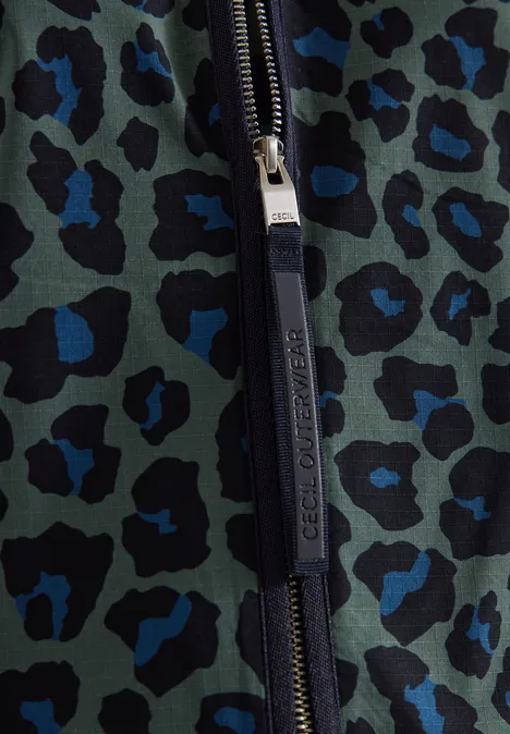Detailaufnahme eines Reißverschlusses auf grünem Stoff mit blau-schwarzem Leopardenmuster