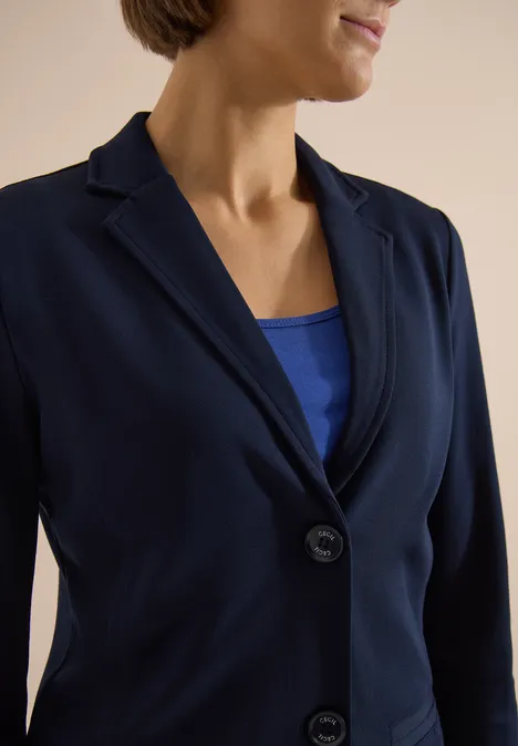 Dunkelblauer Blazer über blauem Top an einer Person, Ausschnitt bis zum Kinn sichtbar.