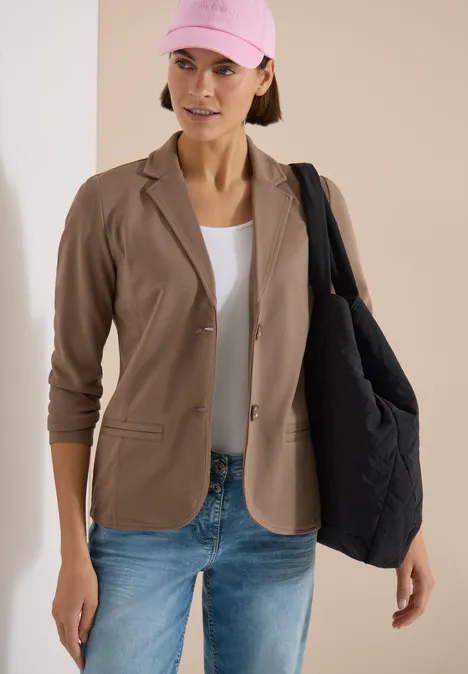 Model mit beigem Blazer, weißem Top, Jeans und schwarzer Stepp-Shopper-Tasche
