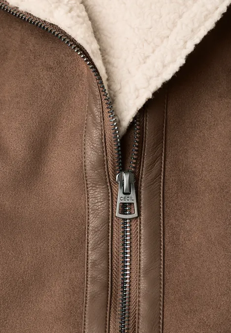 Braune Wildlederjacke mit Reißverschluss und hellem Teddyfellfutter, Nahaufnahme.