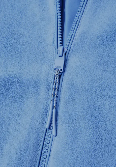 Close-up van een lichtblauwe fleece met zichtbare ritssluiting en ritstrekker.