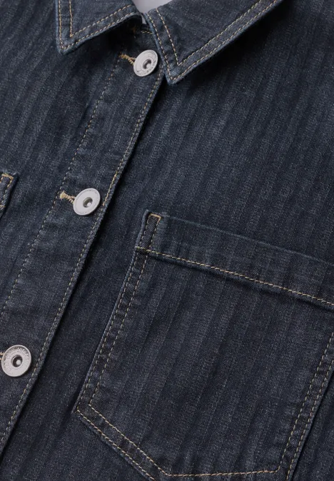 Nahaufnahme eines dunkelblauen Jeanshemds mit feinen Streifen, silbernen Knöpfen und aufgesetzter Brusttasche.