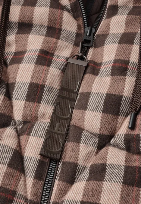 Nahaufnahme einer karierten, wattierten Jacke mit Reißverschluss und Markenanhänger.