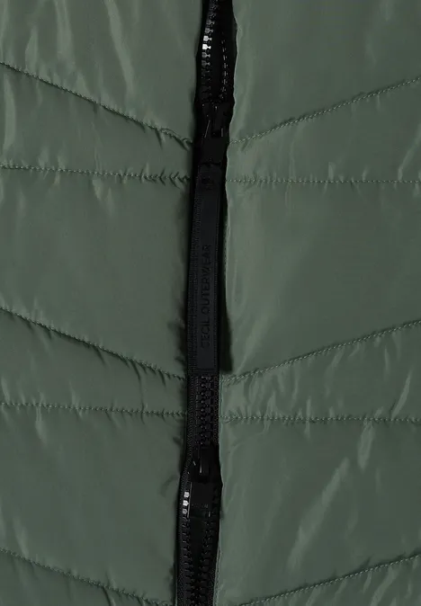 Gros plan sur une veste matelassée verte avec fermeture éclair noire.