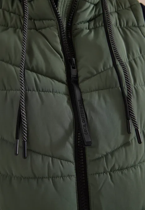 Gros plan d'une veste matelassée verte foncée avec fermeture éclair noire et cordons.