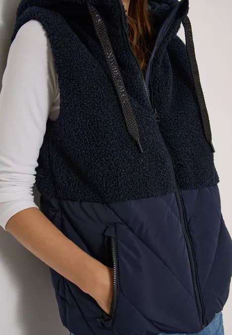 Veste sans manches bleu marine avec haut en polaire et bas matelassé, poches latérales zippées.