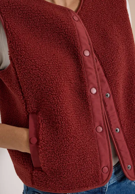 Teddy-Weste mit Softshelldetails russet red Rote ärmellose Teddy-Fleece-Weste mit Druckknöpfen und Taschen.